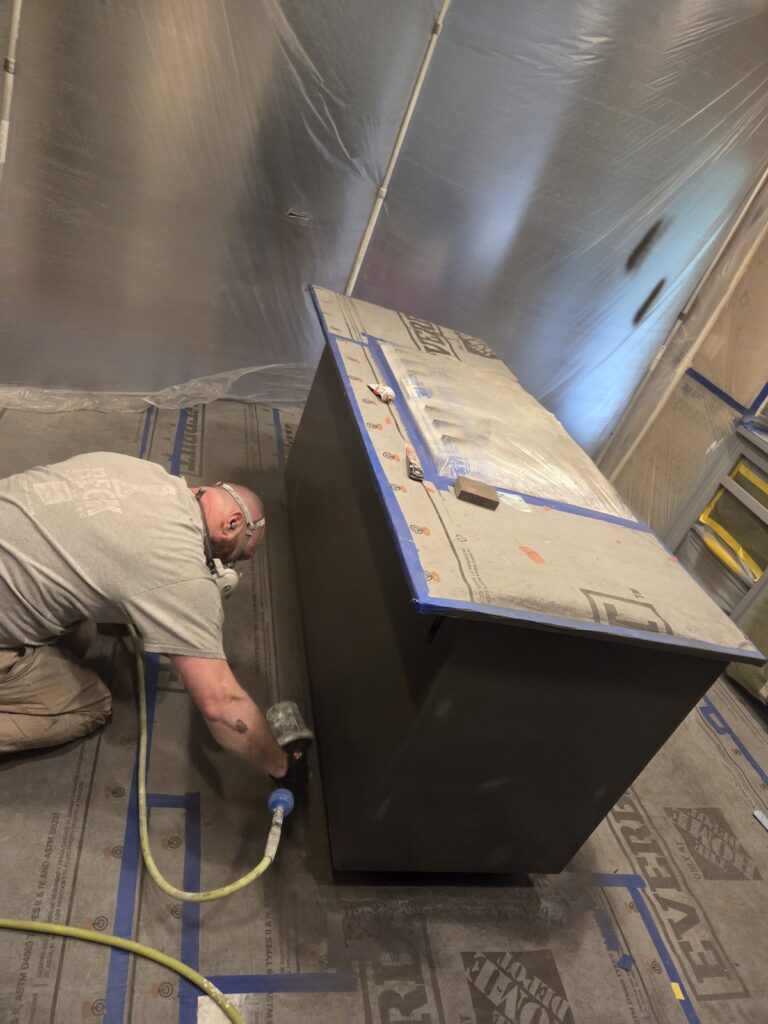 Spraying coats of polyurethane coatings on center island cabinets